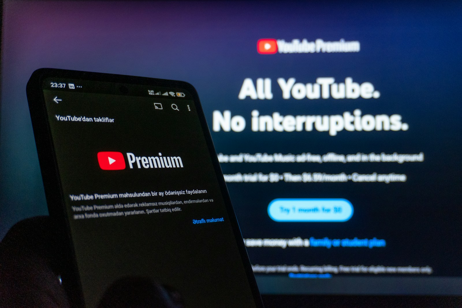 Smartphone displaying youtube premium next to TV screen.